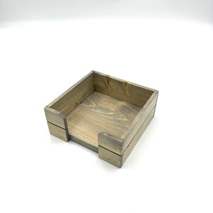 May include: A wooden tissue box holder with a gray stain finish. The box is made of natural wood and has a simple, rustic design.