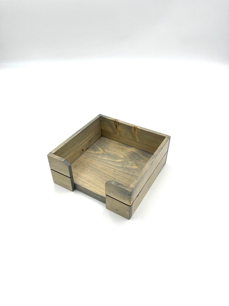 May include: A wooden tissue box holder with a gray stain finish. The box is made of natural wood and has a simple, rustic design.