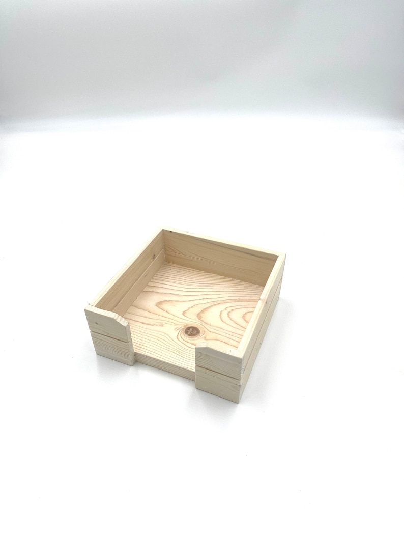 May include: A natural wood square tissue box holder with a simple design. The holder is made of unfinished wood and has a slot for tissues to be pulled out.