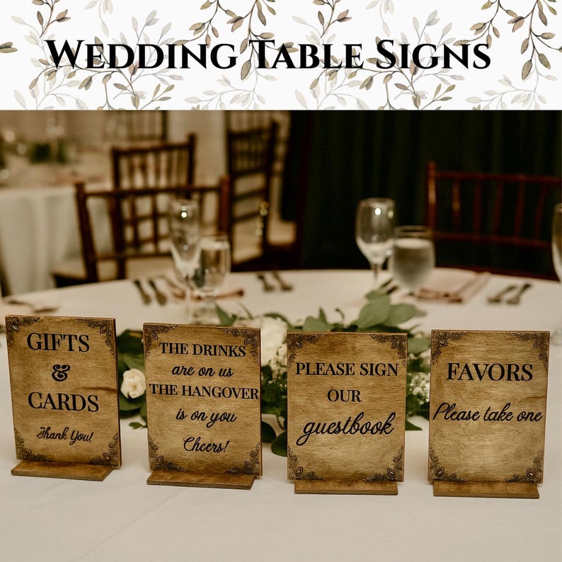 May include: Four wooden wedding table signs with text: "GIFTS & CARDS Thank You!", "THE DRINKS are on us THE HANGOVER is on you Cheers!", "PLEASE SIGN our guestbook", and "FAVORS Please take one". The signs are brown with decorative borders.