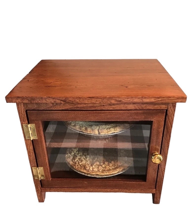 Wooden pie safe with two pie compartments. The front has a door with gold toned hardware, and a transparent Lexan face.