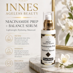 Puede incluir: Un frasco de suero facial blanco y dorado con el texto "INNES Ageless Beauty Niacinamide Prep + Balance Serum". El frasco est&aacute; sobre una superficie de m&aacute;rmol con una flor blanca y un marco dorado en el fondo. El suero es de 60 ml.