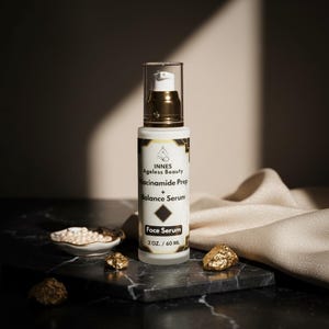 Puede incluir: Botella de s&eacute;rum facial blanca y dorada con el texto "INNES Ageless Beauty Niacinamide Prep + Balance Serum" y "Face Serum 2 oz. / 60 ml". La botella est&aacute; sobre una superficie de m&aacute;rmol negro con detalles dorados.