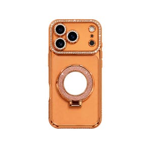 May include: A metallic orange smartphone case featuring a rectangular camera cutout bordered by clear crystals. The back of the case includes a circular, glittery ring stand centered in the middle, also framed by a matching metallic orange border.