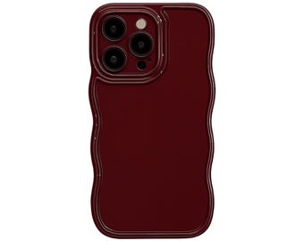 May include: A burgundy-colored phone case with a wavy, textured edge. The case has a glossy finish and features a camera cutout with three lenses and a flash. The design is sleek and modern, offering protection and style.