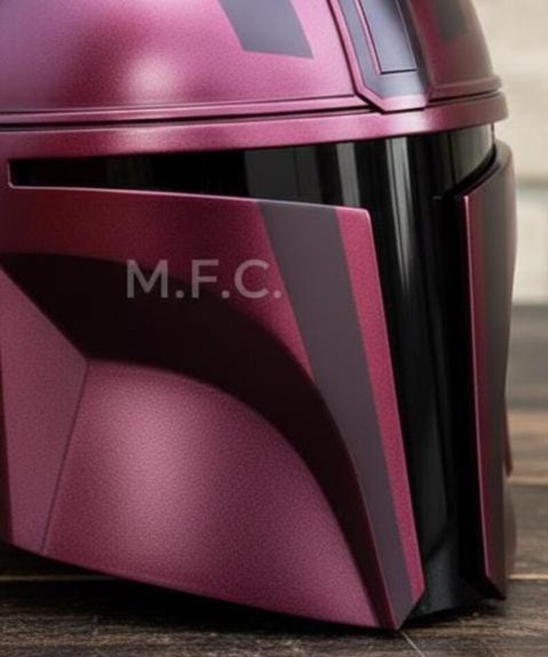 Pu&ograve; includere: Primo piano di un casco bordeaux con dettagli neri. Il casco ha una finitura metallica e le lettere "M.F.C." sono visibili sul lato. Il design presenta forme angolari e un'estetica elegante e moderna.