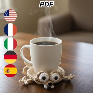 May include: A white mug filled with coffee sits on a handmade crochet coaster shaped like a cartoon character. The coaster is beige with black and white details. The image includes the text "Sid Coaster Crochet Pattern PDF".