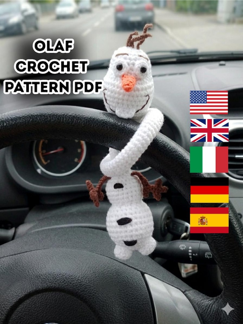 Puede incluir: Un accesorio de coche Olaf de ganchillo blanco con nariz de zanahoria y pelo casta&ntilde;o. El accesorio cuelga del volante de un coche. El texto "OLAF CROCHET PATTERN PDF" es visible.