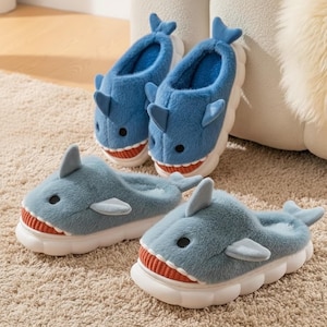 以下が含まれることがあります： サメの形をしたスリッパ4足。スリッパは青色で白いソールで、サメのひれ、目、赤と白の歯の口が特徴です。柔らかく、ふわふわした素材で作られています。