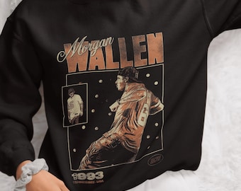 May include: Black sweatshirt featuring a vintage-style graphic of Morgan Wallen. The design includes the name "Morgan Wallen" in a retro font, a picture of a person, and the text "1993 Tennessee USA".