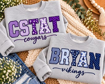 May include: Two light grey crewneck sweatshirts. The top one features purple block letters spelling CSTAT with a cougars script underneath. The bottom one features blue block letters spelling BRYAN with a vikings script underneath.