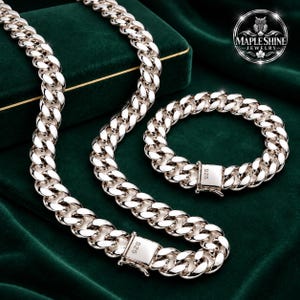 May include: A silver-toned curb chain necklace and a matching curb chain bracelet, both featuring polished interlocking links and a rectangular clasp engraved with the number 925. The jewellery set is displayed alongside a logo reading MAPLESHINE JEWELRY.