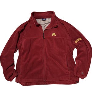 May include: A maroon fleece jacket with a full zipper closure, a stand-up collar, and two side pockets. The jacket features a gold logo on the chest and the words "GOLDEN GOPHERS" on the sleeve.