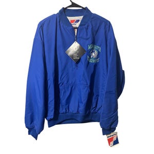 Op de afbeelding: Een blauwe Minnesota Timberwolves pulloverjas met een voorzak en een halve ritssluiting. De jas heeft het teamlogo op de borst en een Swingster-label. Hij hangt aan een zwarte hanger.