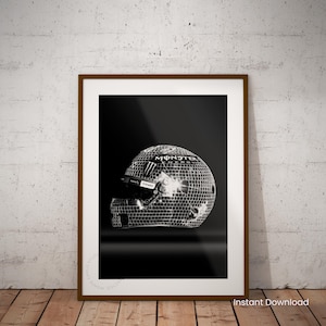 May include: Framed print of a racing helmet with a mirrored disco ball design. The helmet features the Monster Energy logo and is set against a black background. The frame is brown, and the print is on a white background.