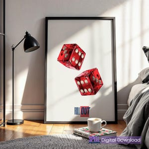 May include: A framed art print featuring two translucent red dice with white dots, seemingly floating against a white background. The word "ROLL OUT" is printed in a bold, stylized font at the bottom. A coffee cup and a book are in the foreground.