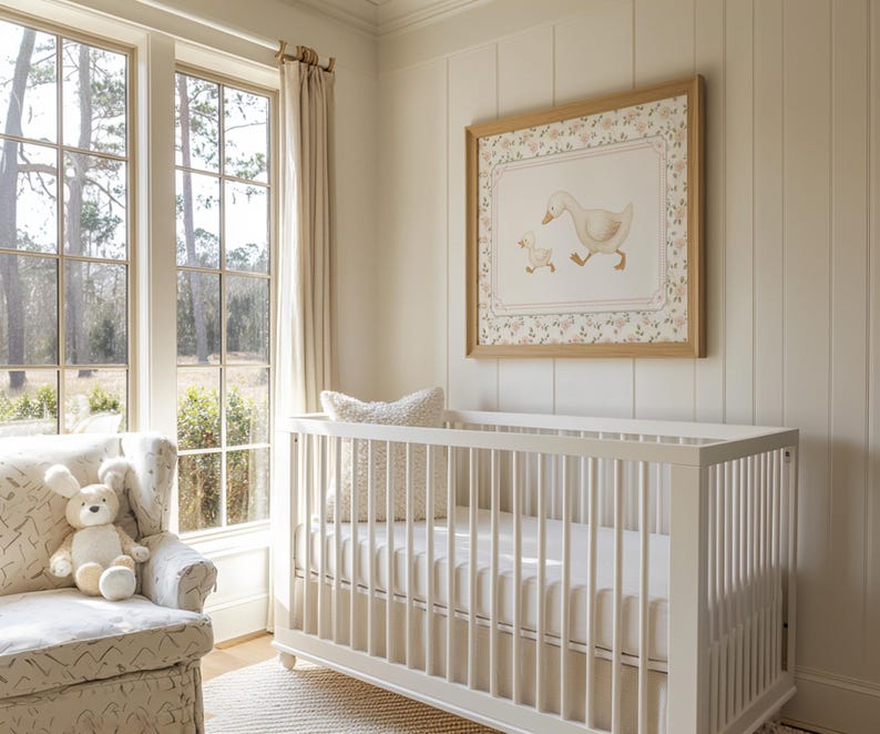 Pode incluir: Um quarto de crian&ccedil;a com um ber&ccedil;o branco, uma poltrona estampada e uma impress&atilde;o emoldurada de um pato e um patinho. O quarto tem janelas grandes com luz natural e paredes e cortinas em tons neutros. Um coelhinho de pel&uacute;cia est&aacute; na poltrona.