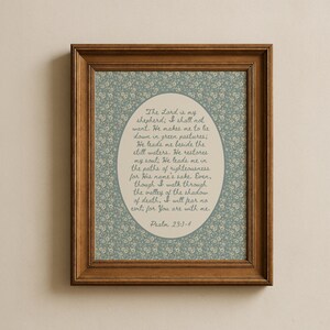 May include: A framed print featuring a floral patterned background in shades of blue and white. The print has a wooden frame. The text within the frame reads "The Lord is my shepherd; I shall not want...Psalm 23:1-4."