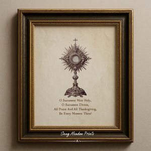 Op de afbeelding: Ingelijste print met een gedetailleerde illustratie van een monstrans, een religieus object, met een kruis. De print bevat de tekst "O Sacrament Most Holy..." en het logo "Snug Meadow Prints". De lijst is donkergroen en goud.