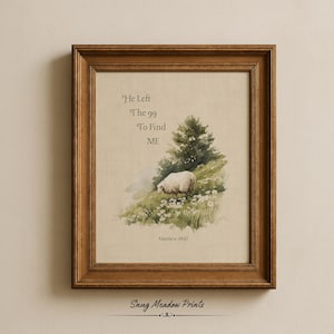 May include: A framed print with a watercolour painting of a sheep on a grassy hill with a tree. The text "He Left The 99 To Find ME" is above the image, with "Matthew 18:12" below. The frame is brown.