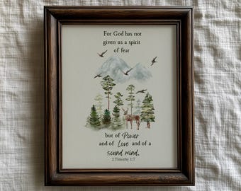 May include: A dark brown wooden frame containing a print with a watercolor mountain and forest scene, a deer, and birds. The text reads: For God has not given us a spirit of fear but of Power and of Love and of a sound mind. 2 Timothy 1:7.