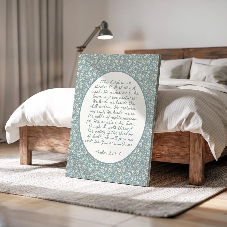 May include: A canvas print featuring a floral pattern in shades of blue and white. The print displays an oval-shaped text box with a religious quote from Psalm 23:1-4 in a handwritten style font. The canvas is displayed on a wooden bed frame.