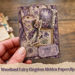 May include: A rectangular paper craft tag featuring a purple floral pattern, a die-cut fairy illustration, a small framed purple flower print, a piece of white lace trim, and a purple ticket with the text TICKET ADMIT ONE printed on it.