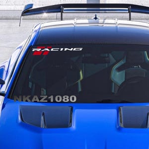 May include: A blue sports car with a black spoiler and a windshield banner that reads "RACING" in white letters with a red and black checkered flag design. The text "NKAZ1080" is visible on the windshield.