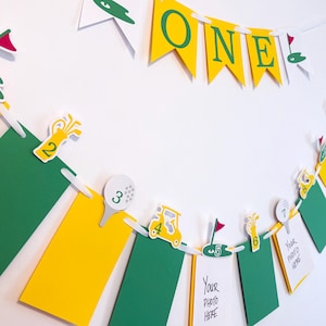 May include: A golf-themed birthday banner with yellow and green pennants. The banner has a white string running through it and includes a golf club, golf ball, golf cart, and the word 