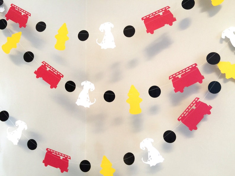 May include: A red, white and black paper garland with fire engine, dalmatian dog and fire hydrant cut-outs. The garland is strung together with black circles.