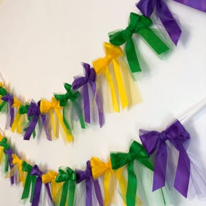 May include: A Mardi Gras party garland with purple, green, and gold bows and tulle streamers.