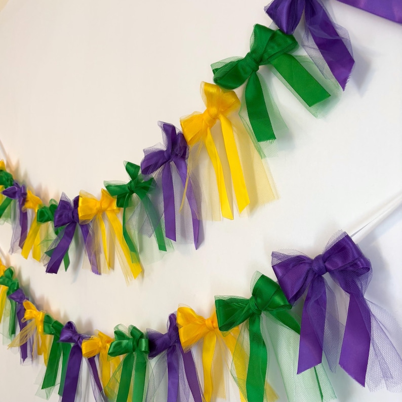 May include: A Mardi Gras party garland with purple, green, and gold bows and tulle streamers.