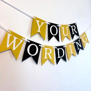 May include: A black and gold banner with the text "YOUR WORDING" in white letters. The banner is made of paper and is strung together with white ribbon.