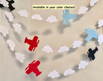 May include: A garland with white paper clouds and airplanes in red, blue, and black. The garland says "Available in your color choices!"