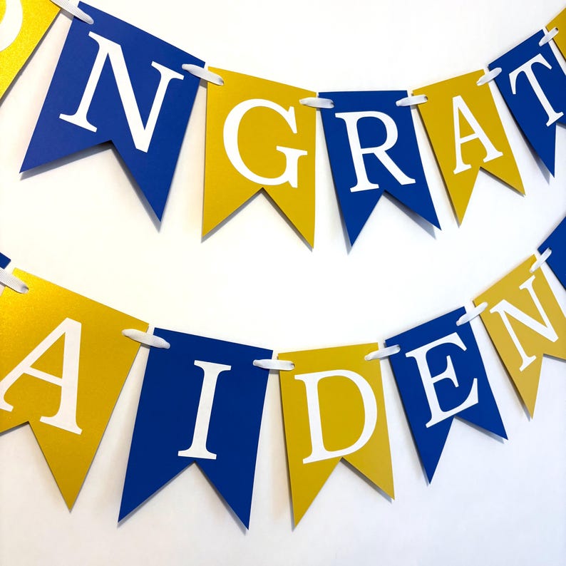 May include: A blue and gold banner with the words "CONGRATULATIONS" and "AIDEN" in white letters.