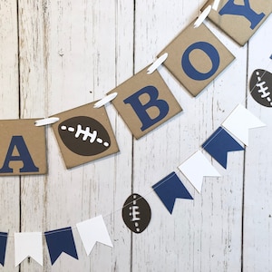May include: A brown and white banner with the word "BOY" in blue letters, decorated with brown footballs and blue and white pennants.