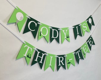 May include: Green and black banner with white letters that reads "Cody is Thirty" with golf ball and golf cart graphics.