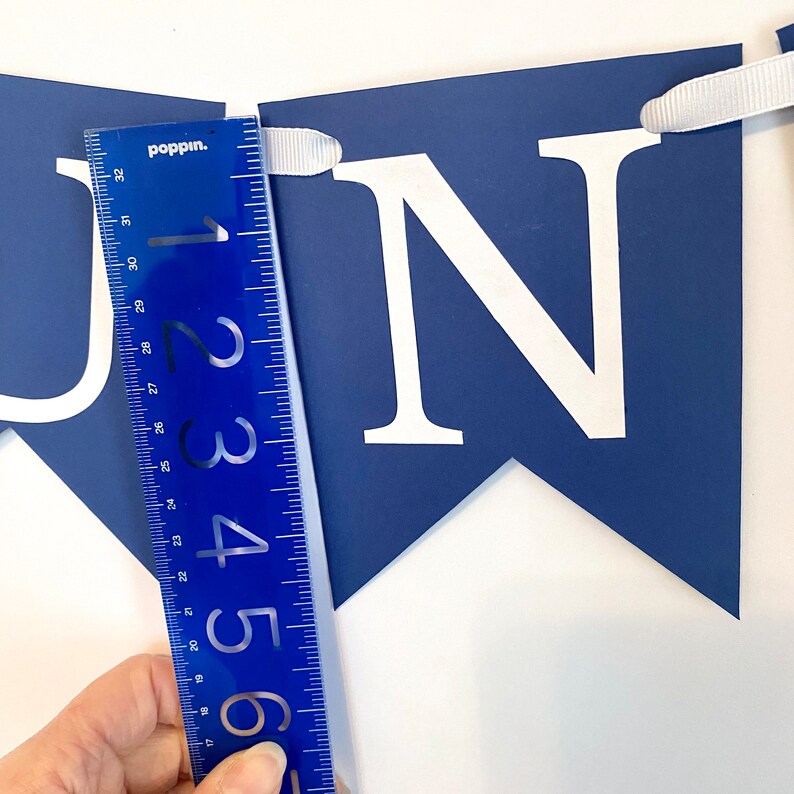 May include: A blue banner with white letters spelling "JUNE" with a ruler measuring 6 inches in length.