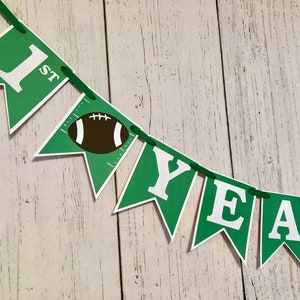 May include: Green and white felt banner with the words "1st" and "YEAR" with a football graphic in the middle.