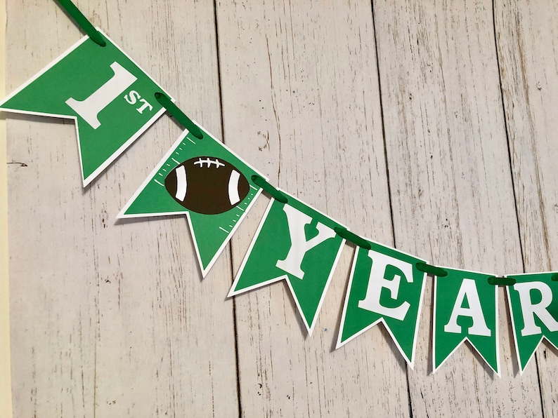 May include: Green and white felt banner with the words "1st" and "YEAR" with a football graphic in the middle.