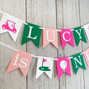 May include: A pink, green, and white banner with the text 