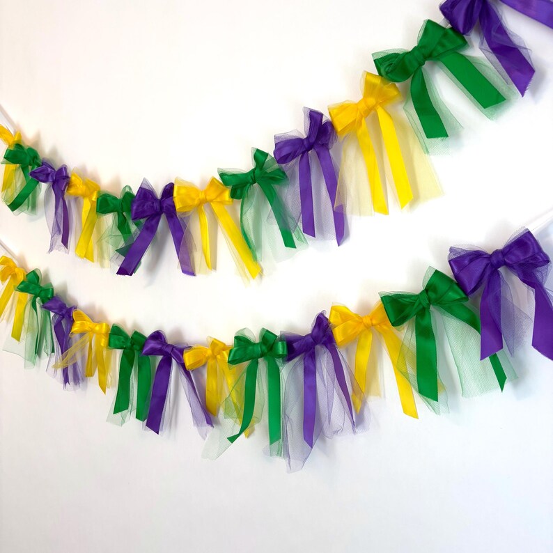 May include: A Mardi Gras party garland with purple, green, and gold bows and tulle streamers.
