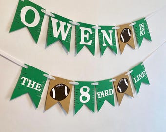 May include: Green and brown banner with white text that reads "Owen is at the 8 yard line". The banner has football graphics.