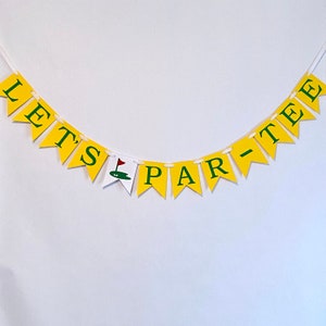 May include: A yellow and green banner with the text "Let's Par-Tee" in white letters. The banner is strung together with white string and has a small green golf flag icon in the center.