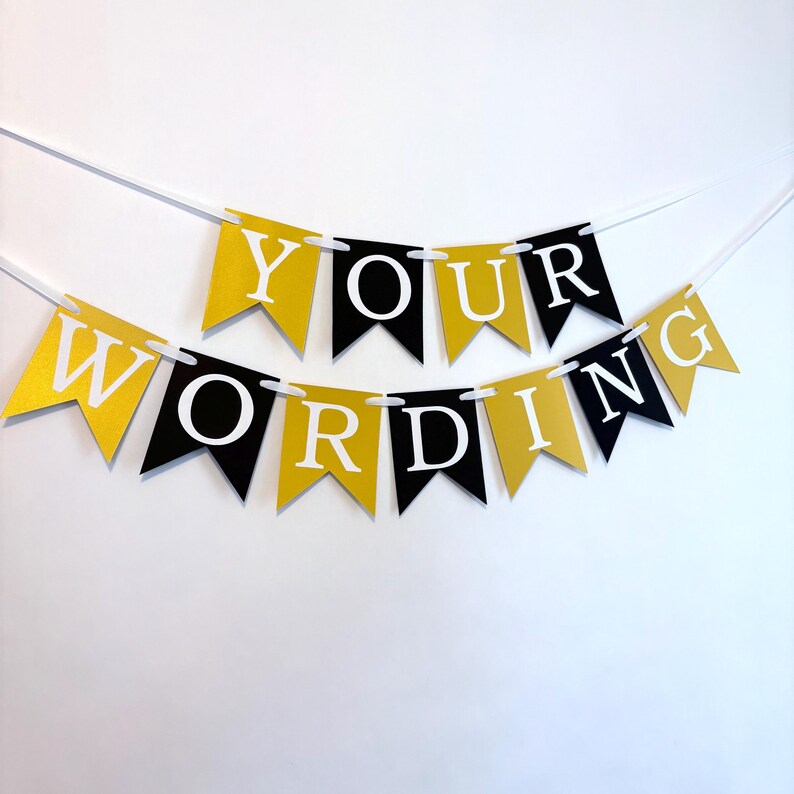 May include: A black and gold banner with the text "YOUR WORDING" in white letters. The banner is made of paper and has a string attached to it.