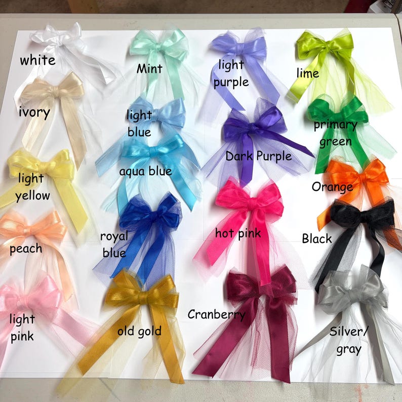May include: A collection of 18 tulle bows in various colors, including white, ivory, light yellow, peach, light pink, mint, light blue, aqua blue, royal blue, old gold, light purple, dark purple, hot pink, cranberry, lime, primary green, orange, black, and silver/gray.