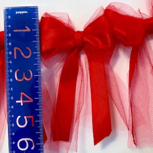 May include: Red tulle and satin ribbon bow garland. The garland is approximately 6 inches long and features multiple bows.