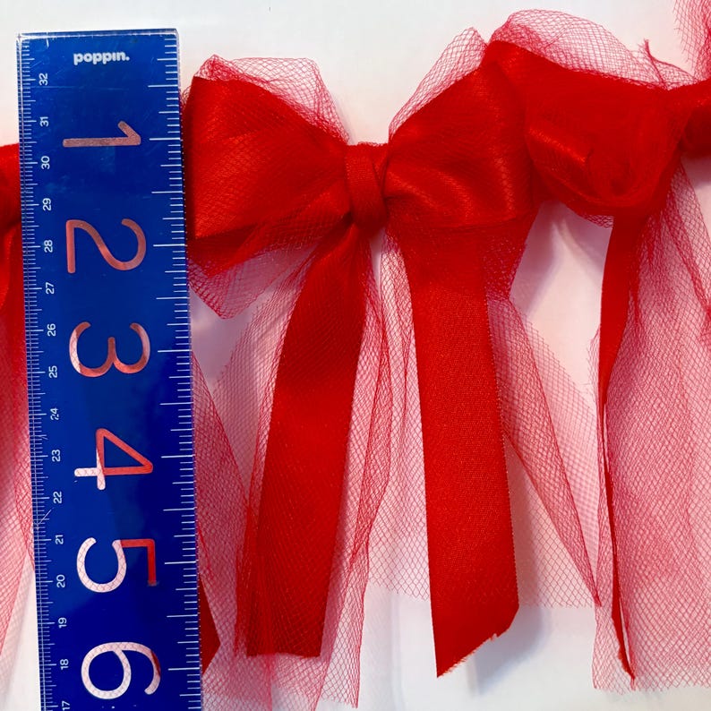May include: Red tulle and satin ribbon bow garland. The garland is approximately 6 inches long and features multiple bows.