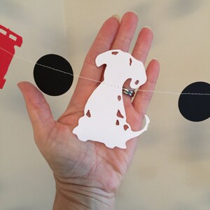 May include: White paper cutout of a Dalmatian dog with black spots hanging on a string with black circles and a red paper cutout of a fire hydrant.