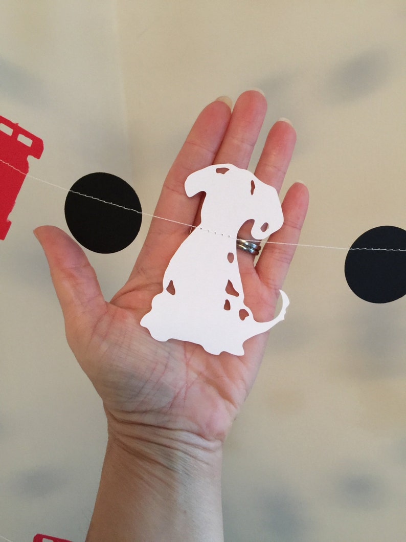 May include: White paper cutout of a Dalmatian dog with black spots hanging on a string with black circles and a red paper cutout of a fire hydrant.